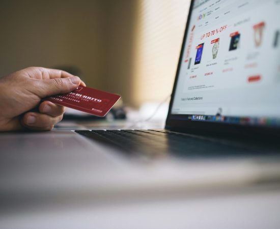 Person holding a credit card while shopping online on a laptop, indicating ecommerce transactions.