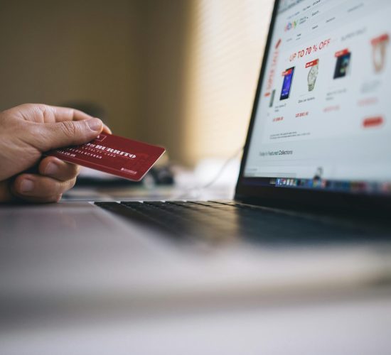 Person holding a credit card while shopping online on a laptop, indicating ecommerce transactions.